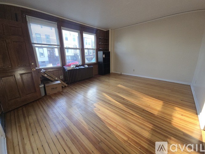A room with wooden floors and a window overlooking a street.