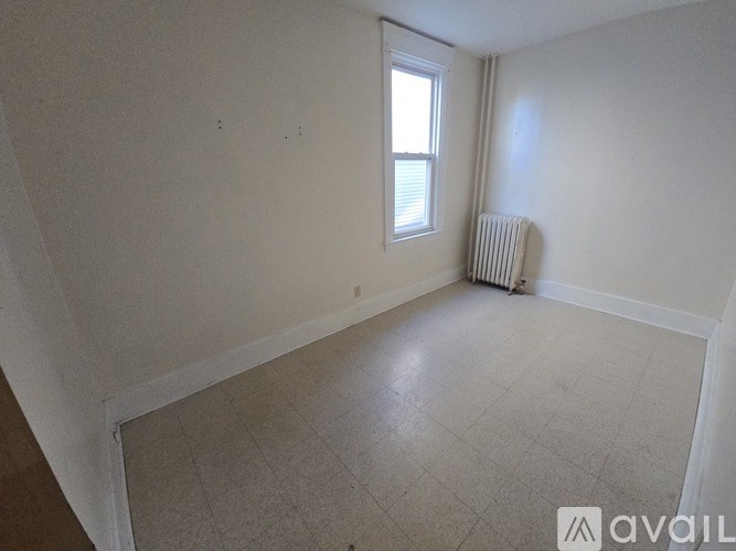 A room with a window and a radiator on the floor.