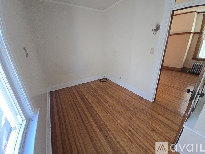 A room with wooden flooring and white walls.
