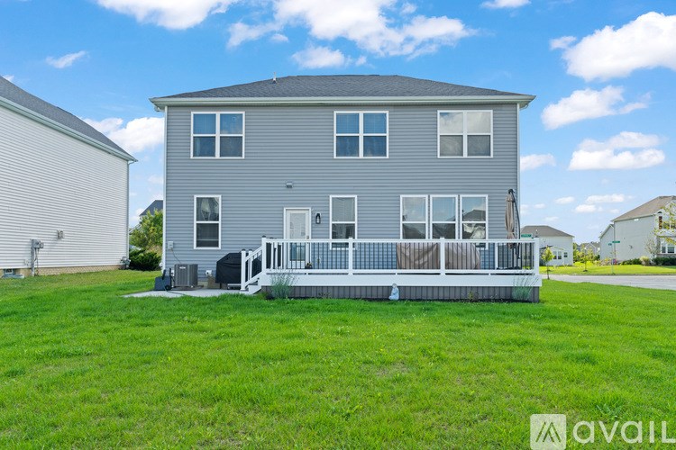 A grey house with a deck in the front yard.