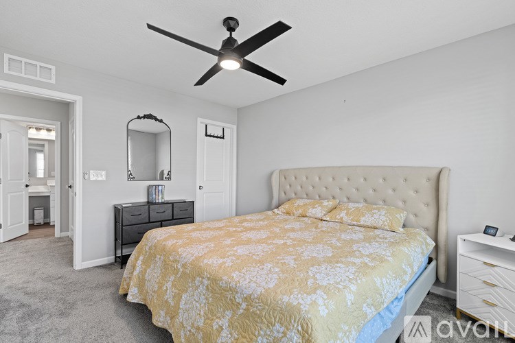 A bedroom with a bed, dresser, mirror, and a ceiling fan.