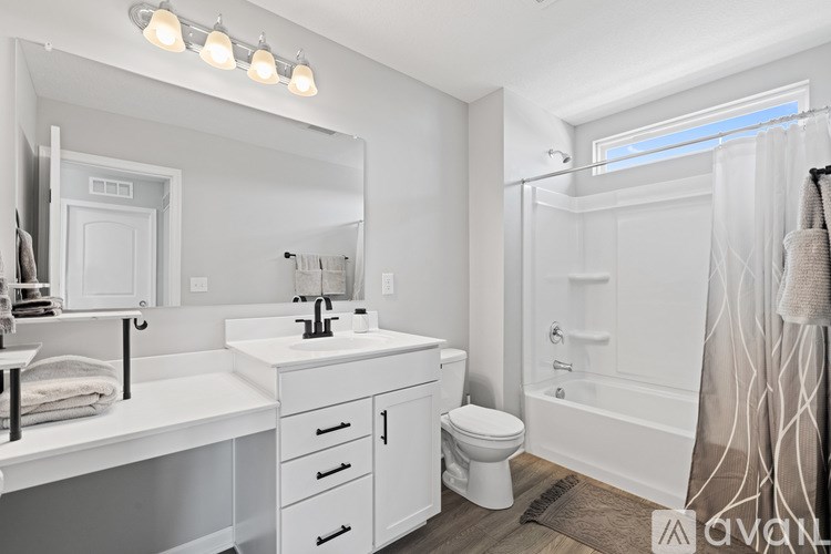 A white bathroom with a toilet, sink, and mirror.