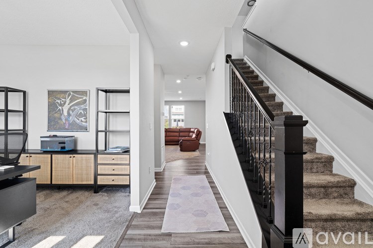 A hallway with a staircase and a desk with a computer on it.