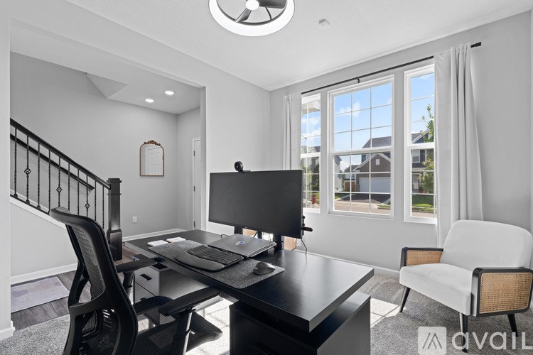 A modern home office with a black desk and a television.