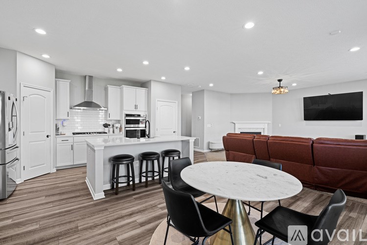 A modern kitchen with a white island and a brown leather couch.