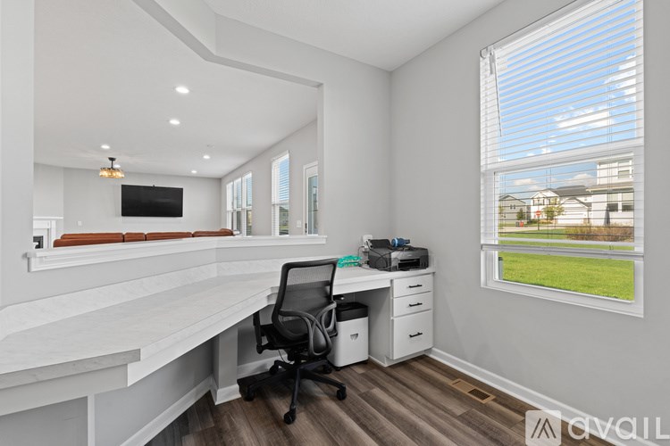 A white desk with a black chair and a TV on the wall.