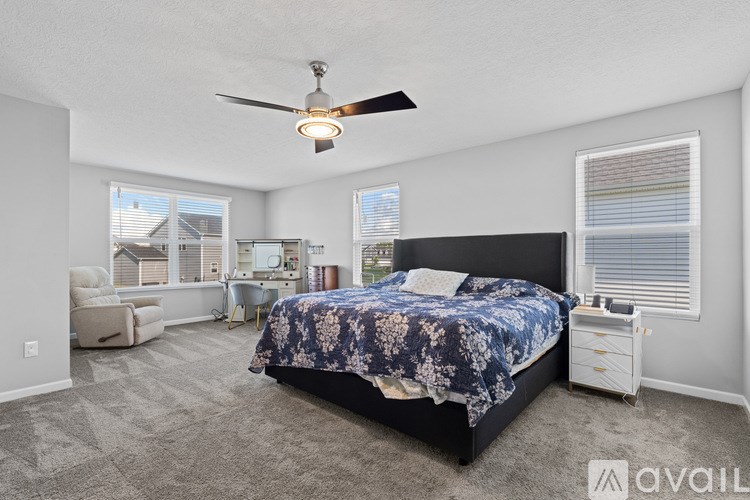 A bedroom with a bed, chair, and ceiling fan.