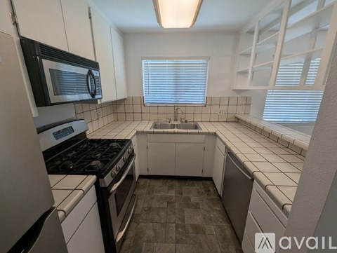 A kitchen with black and white appliances and white cabinets.