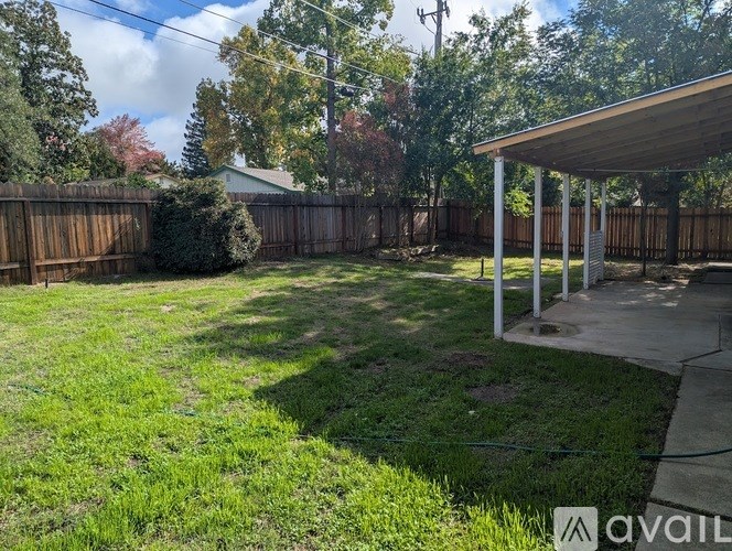 A backyard with a wooden fence and a covered patio area.