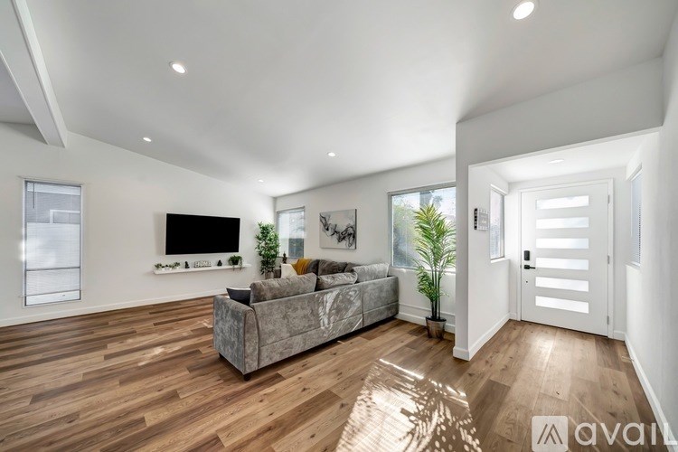A living room with a grey couch and a television on the wall.