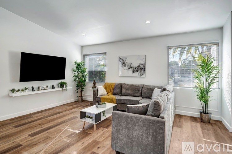 A living room with a grey couch, a coffee table, and a large window.