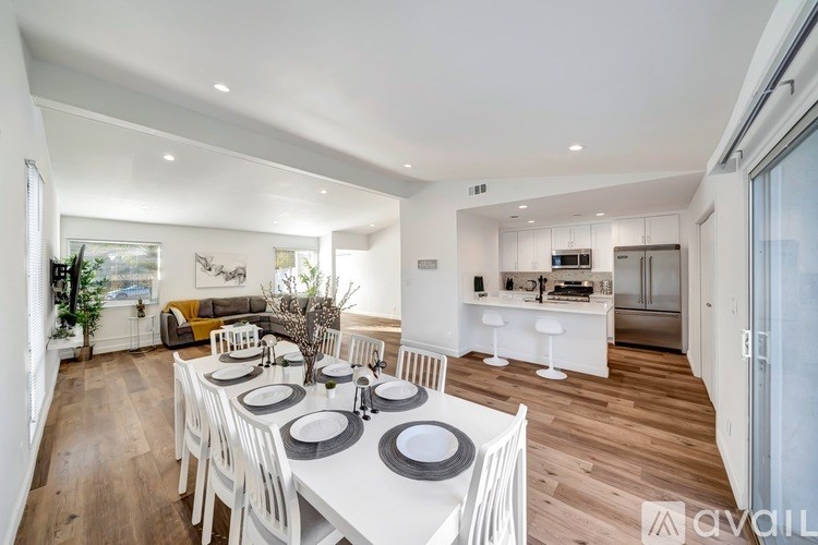 A modern dining room with a white table set for six.