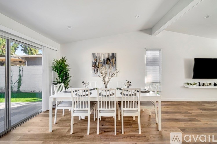 A dining room with a white table and chairs.