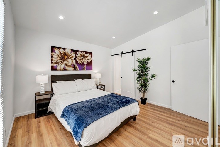 A bedroom with a bed, nightstand, and a painting on the wall.