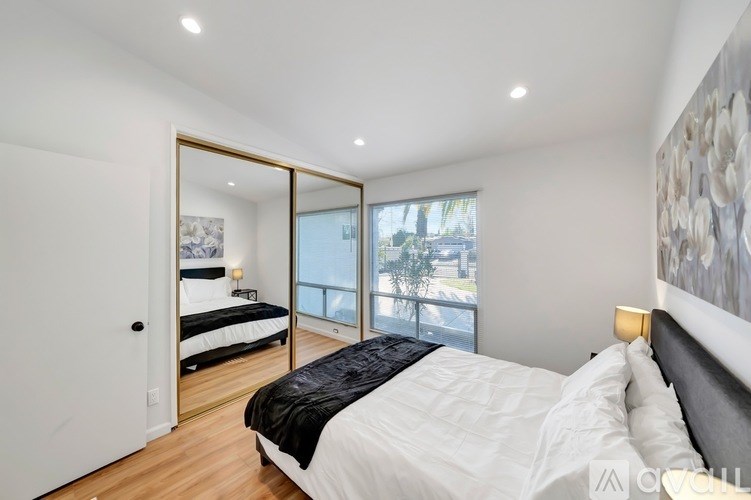 A bedroom with a large bed and a mirrored doorway leading to a balcony.