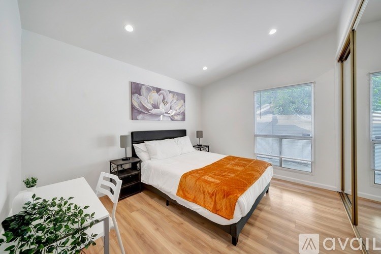 A bedroom with a bed, a chair, and a painting on the wall.