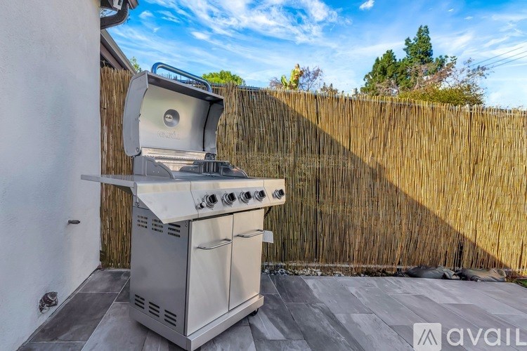 A white outdoor grill with a side burner is on a patio.