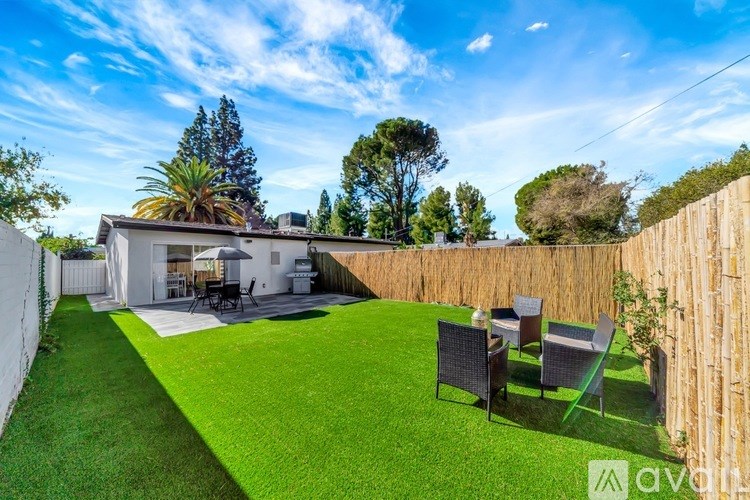 A backyard with a lawn and chairs.