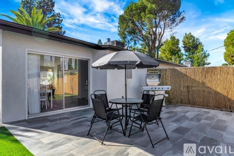 A patio with a table and chairs and an umbrella.