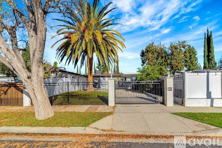 A gated entrance to a residential area with a palm tree in the foreground.