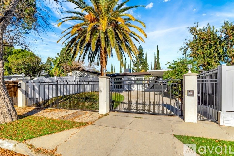 A gated entrance to a property with a palm tree in the foreground.