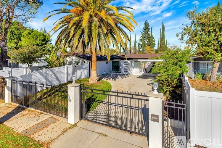 A house with a black gate and a palm tree in front.