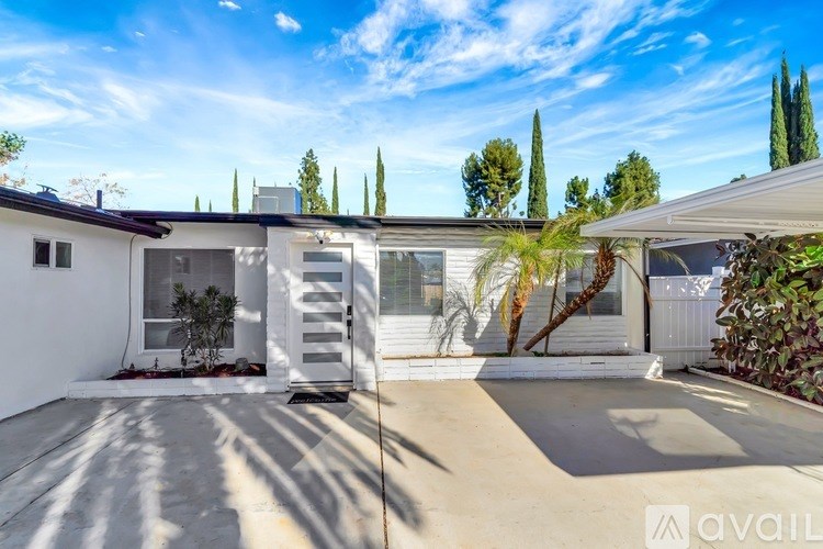 A modern house with a white exterior and a large driveway.
