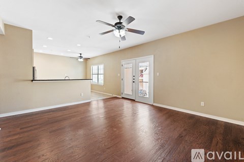A spacious room with a ceiling fan and wooden flooring.