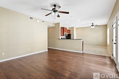 A spacious room with wood flooring and a ceiling fan.