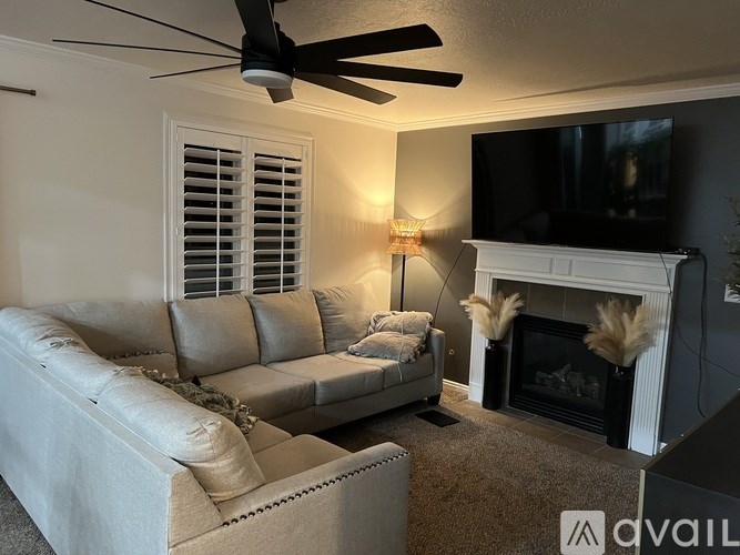 A living room with a grey couch, a fireplace, and a television.