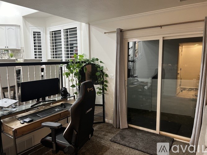 A black gaming chair sits in front of a desk with a computer.