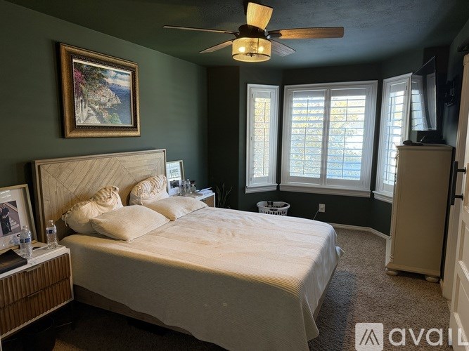 A bedroom with a bed, a ceiling fan, and a window with blinds.
