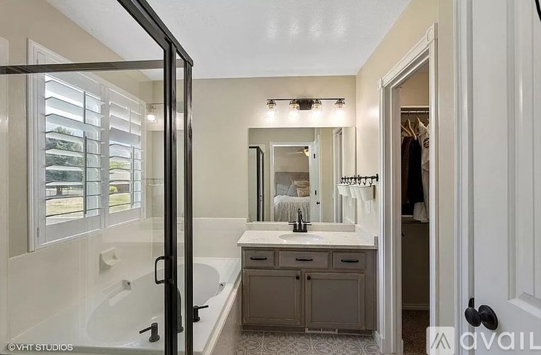 A bathroom with a tub, sink, and mirror.