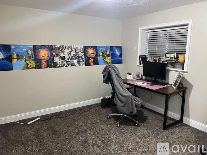 A room with a desk, chair, and pictures on the wall.