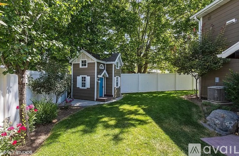 A small house with a blue door is surrounded by a well-kept lawn and trees.