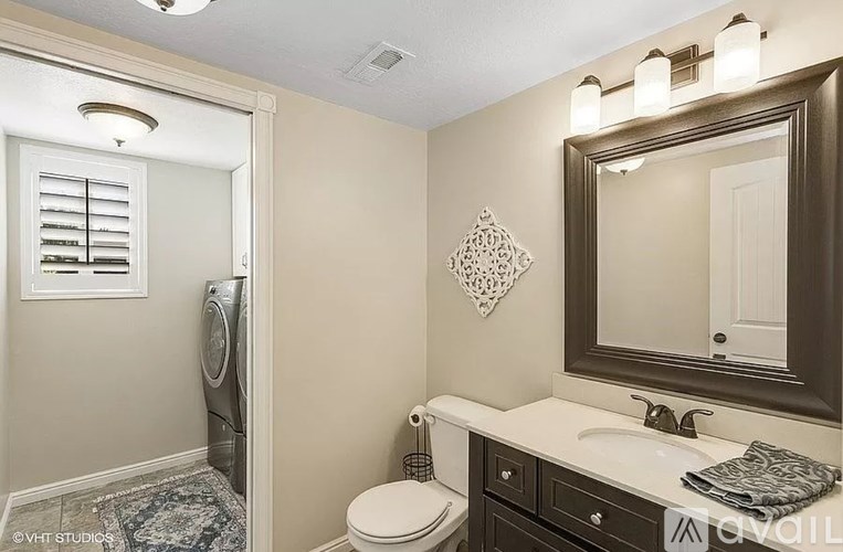 A bathroom with a toilet, sink, mirror, and a rug.
