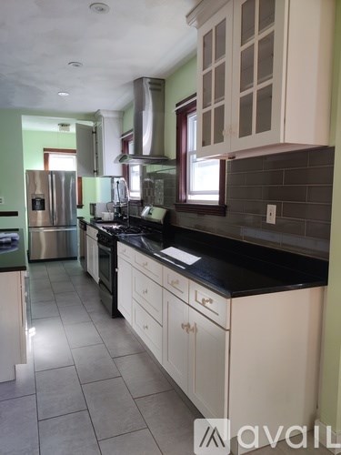 A kitchen with white cabinets and a black countertop.