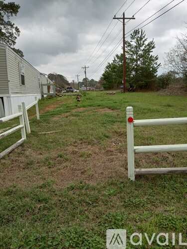 A white fence in a grassy field with a house in the background.