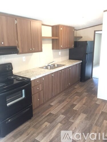 A kitchen with wooden cabinets and a black refrigerator.