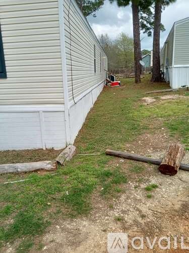 A grassy area in front of a house with a fallen tree trunk.