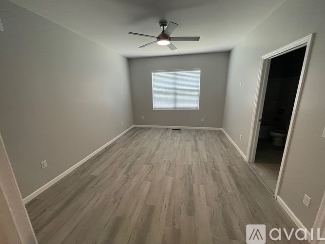 A room with a ceiling fan and wooden flooring.