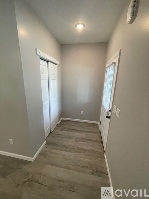 A room with a carpeted floor and a window with blinds.