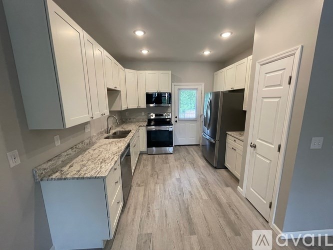 A kitchen with white cabinets and a granite countertop.