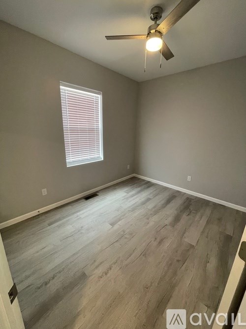A room with a ceiling fan and a window with blinds.