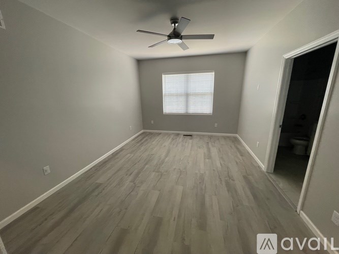 A room with a ceiling fan and wooden flooring.