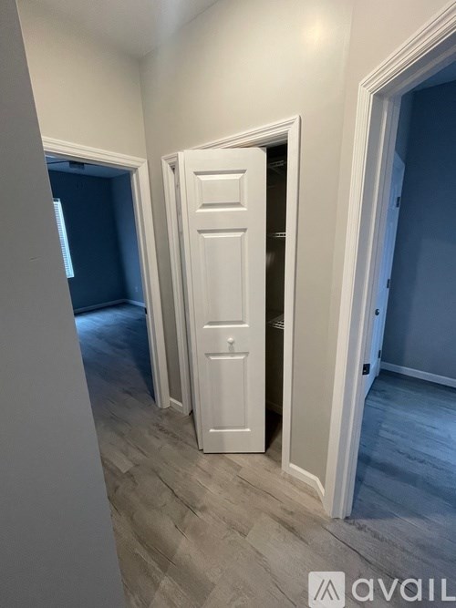A white door is open in a room with wooden flooring.