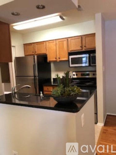 A kitchen with a black counter top and wooden cabinets.