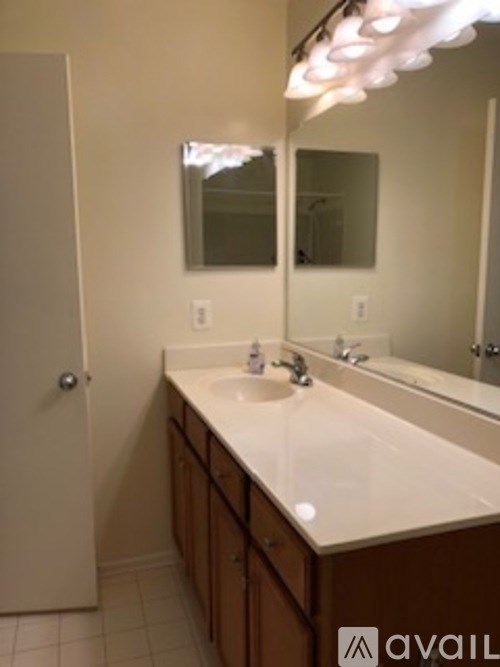 A bathroom with a white counter top and a mirror above it.