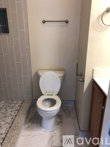 A white toilet with a white lid is in a bathroom with a white toilet paper holder.