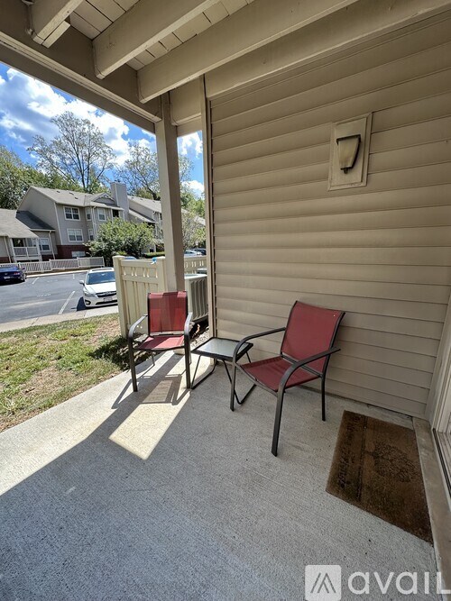 Two chairs are on a porch with a doormat in front of them.